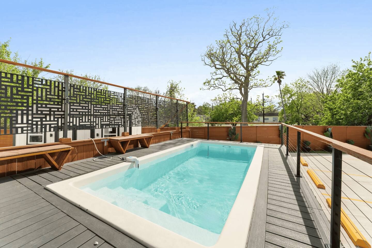 Ein Dachpool mit Holzboden, Metallgeländern und einem dekorativen Zaun.