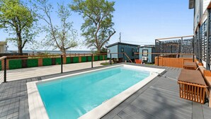 A swimming pool with a wooden deck, a covered seating area, and a view of the sea. - Waterfront Tiny Suite | Cal King + Bay Views|Kemah (Bacliff)