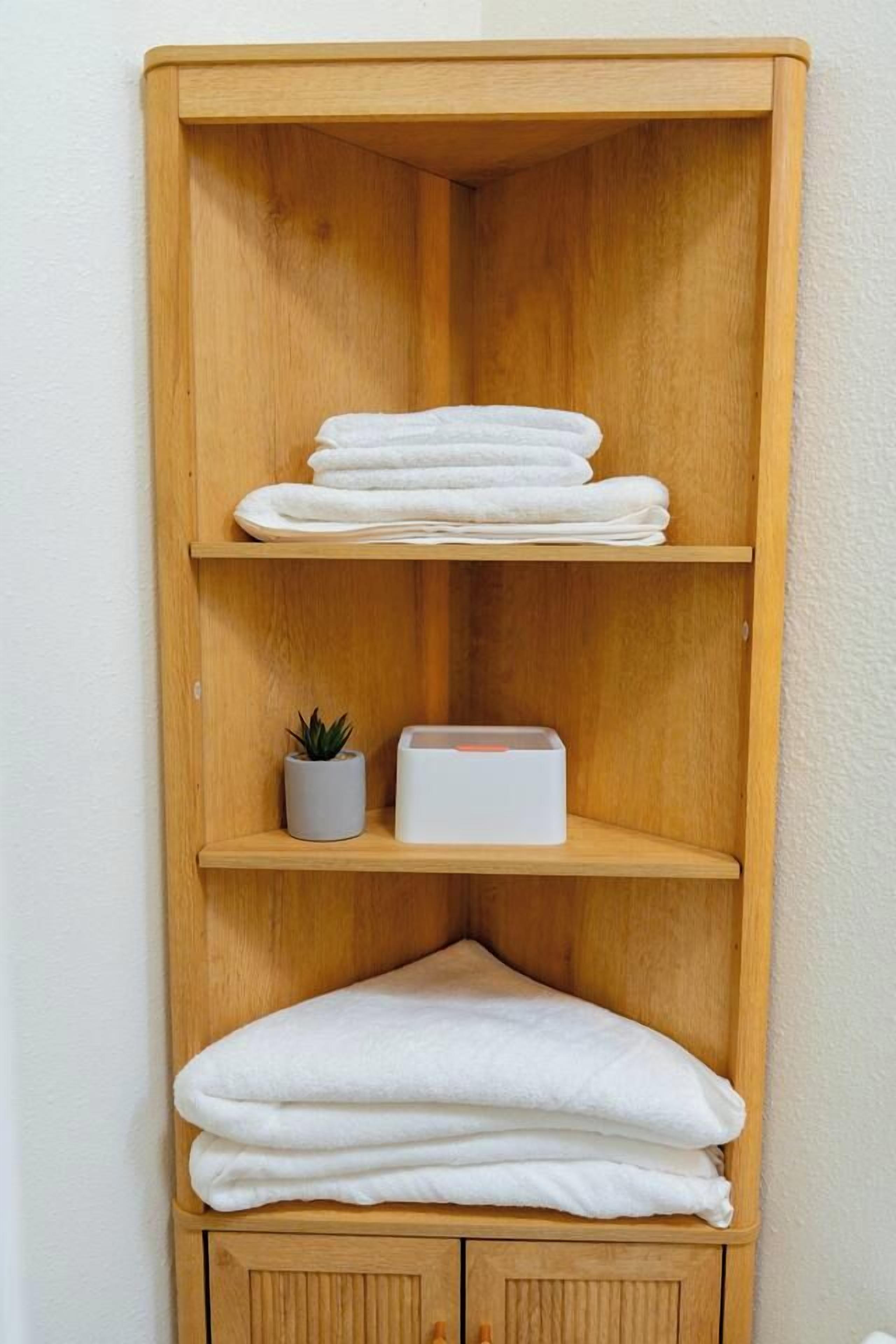 A wooden shelf unit with folded towels and a small potted plant.