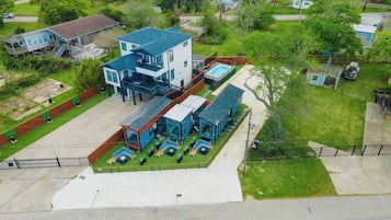 Un edificio moderno de dos pisos con piscina, zona de estar exterior y un patio cubierto.