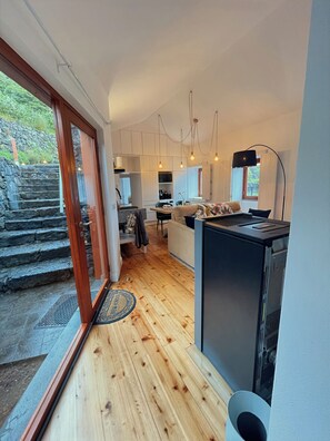 Cozinha moderna com piso de madeira, área de jantar e vista para uma escadaria de pedra que dá para o exterior.