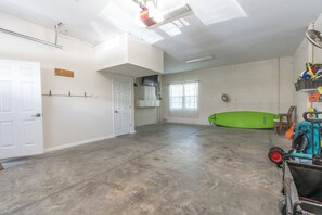 A spacious room with a concrete floor, a large window, and a green surfboard. - Turtle Tales on Anna Maria I Pool & Hot Tub I Bermuda Bay Club (Bradenton Beach)