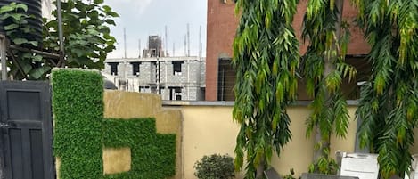 Una piscina con un flotador salvavidas, rodeada por un patio empedrado, una pequeña mesa con sillas y una pared con plantas.
