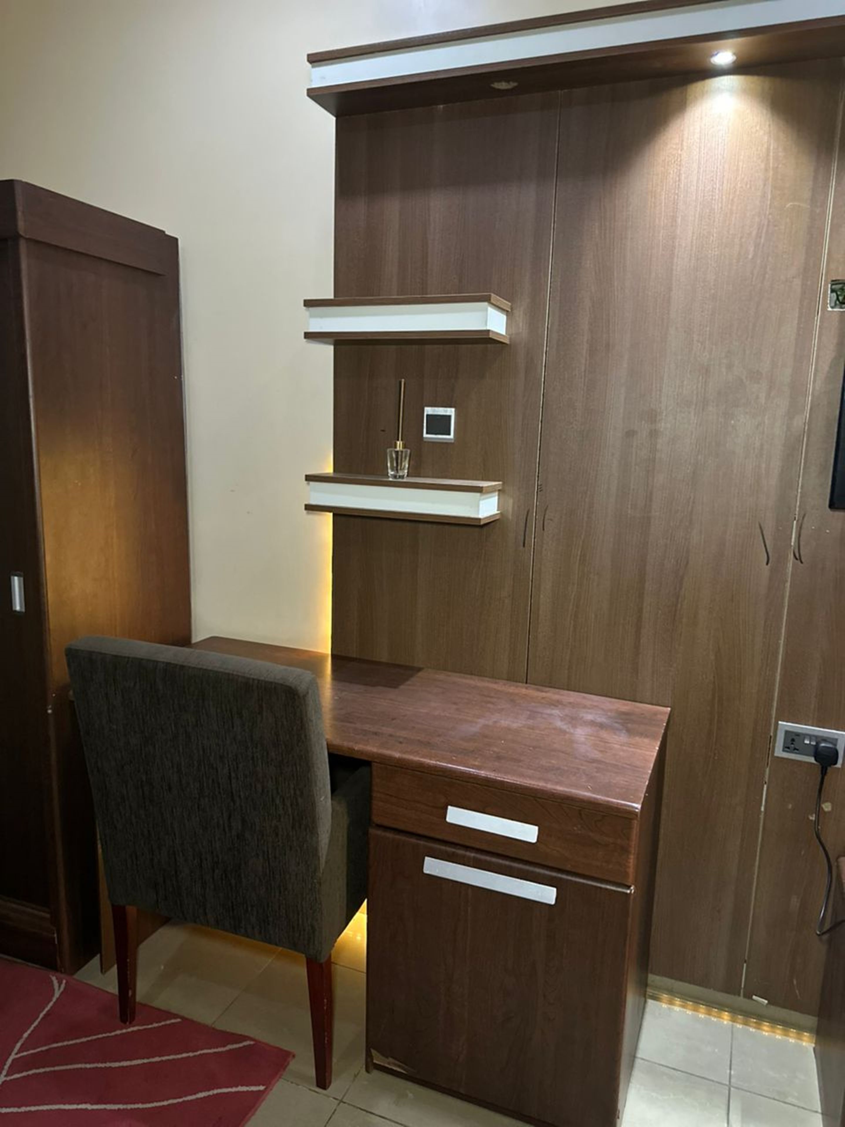 Una habitación con un escritorio de madera, una silla y un armario.