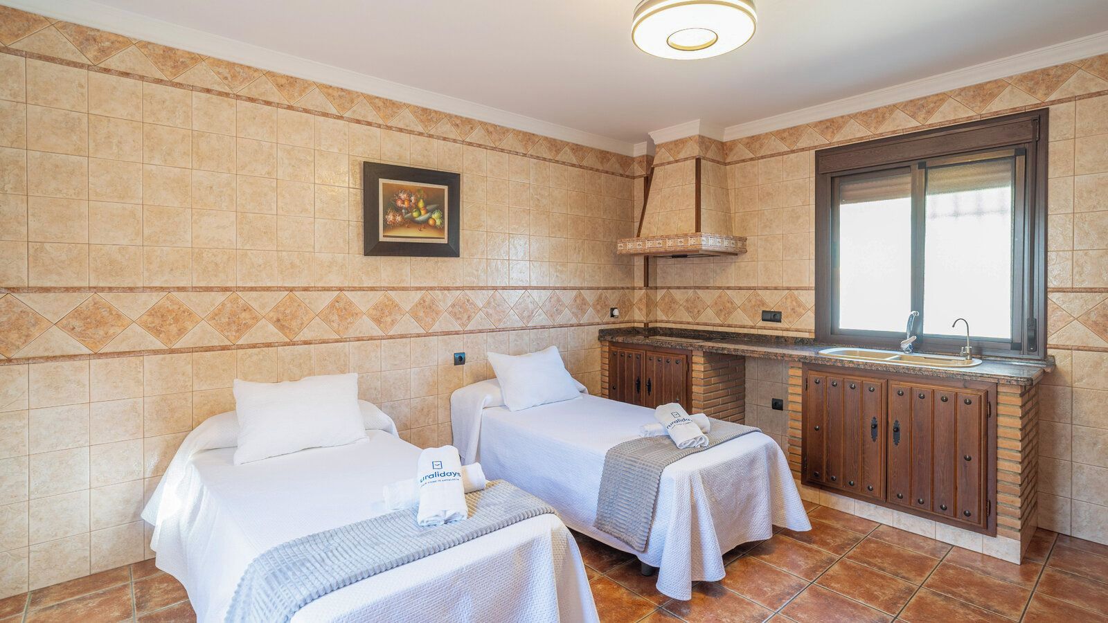 Habitación de hotel con dos camas, kitchenette y ventana.