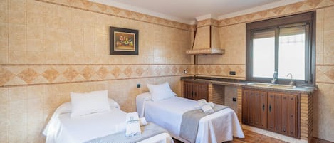 Habitación de hotel con dos camas, kitchenette y ventana.
