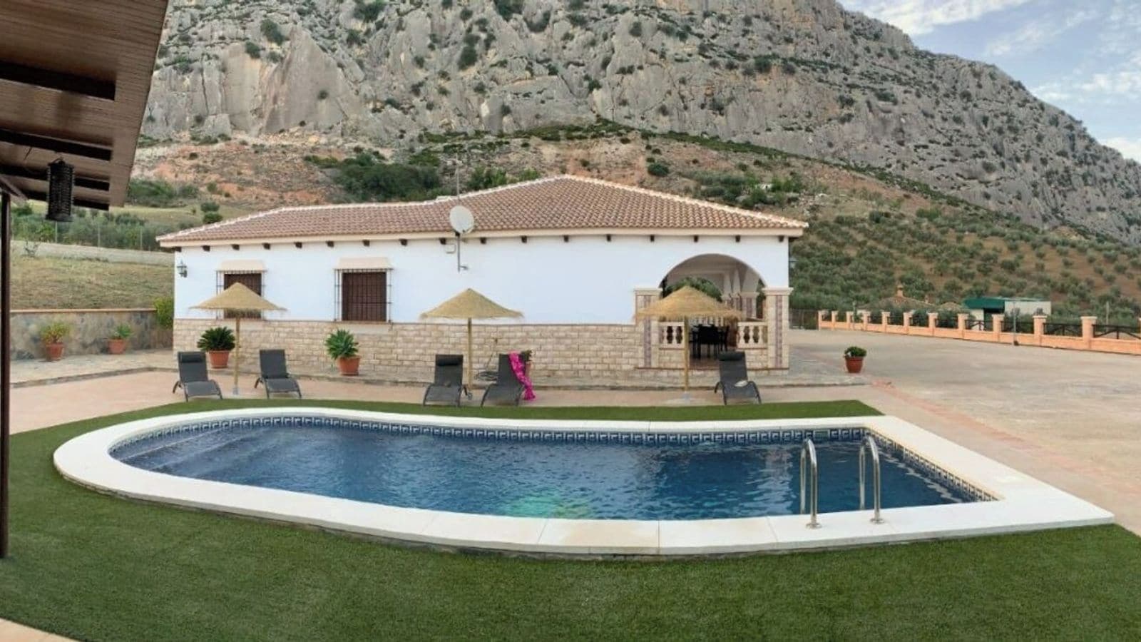 Une maison avec une piscine, un espace salon extérieur et un paysage montagneux en toile de fond.