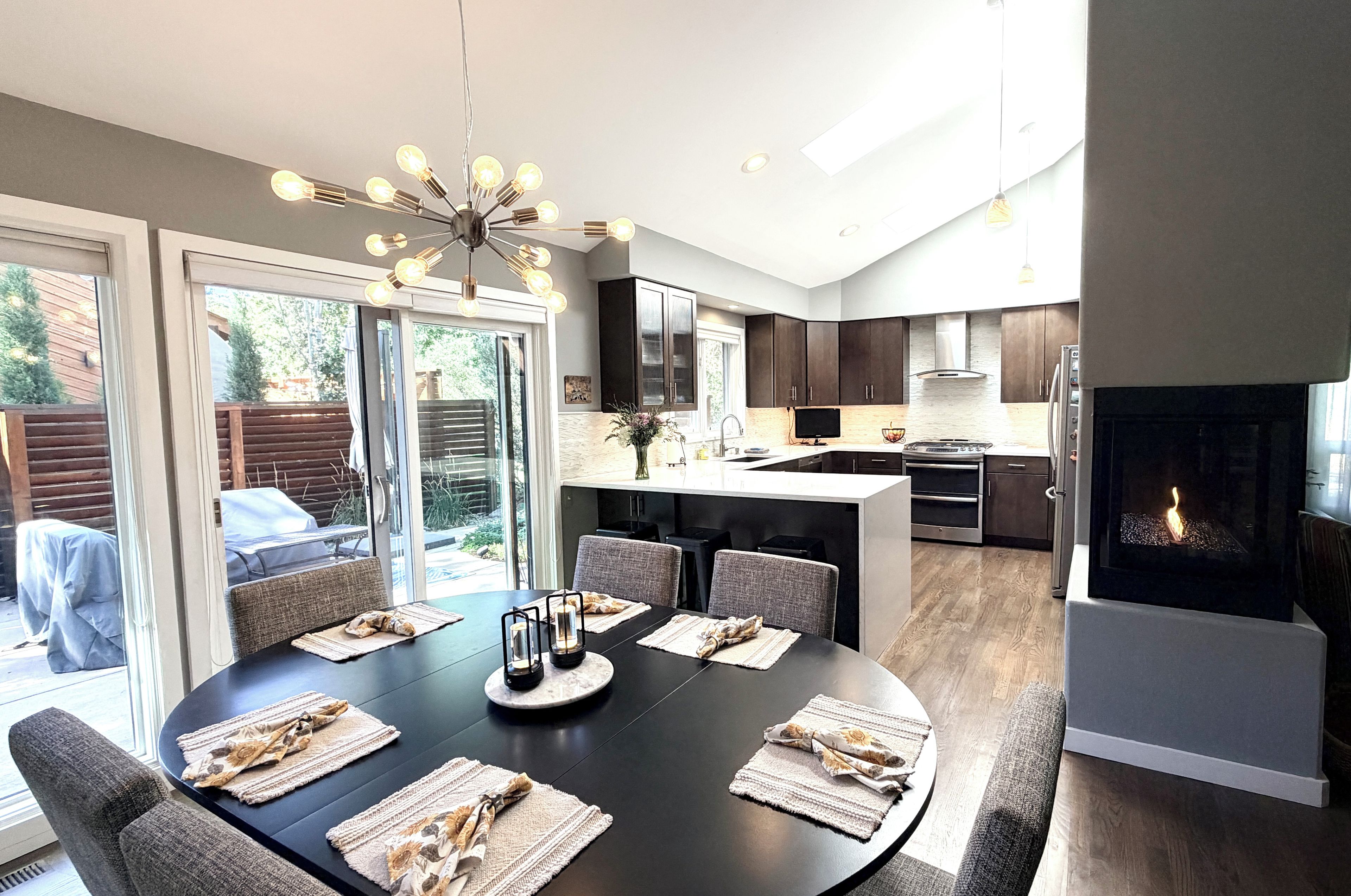 A modern kitchen with dark cabinets, a central island, and a built-in oven.