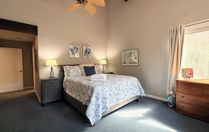 A bedroom with a bed, two bedside tables, a nightstand, a ceiling fan, a window with curtains, and wall art. - Bright & Spacious 3BR/2BA Home Close to Downtown and Sundance Film Festival (Boulder)