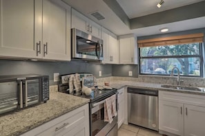 A modern kitchen with stainless steel appliances, granite countertops, and a window with a view of the outside. - Near Tampa, St. Pete & Top Beaches + Pet-Friendly! (Largo)