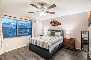 A bedroom with a bed, a nightstand, a dresser, a ceiling fan, and a window with curtains. - Near Tampa, St. Pete & Top Beaches + Pet-Friendly! (Largo)