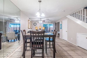 A spacious dining area with a large table and chairs, a ceiling fan, and a view of the backyard through glass doors. - Near Tampa, St. Pete & Top Beaches + Pet-Friendly! (Largo)