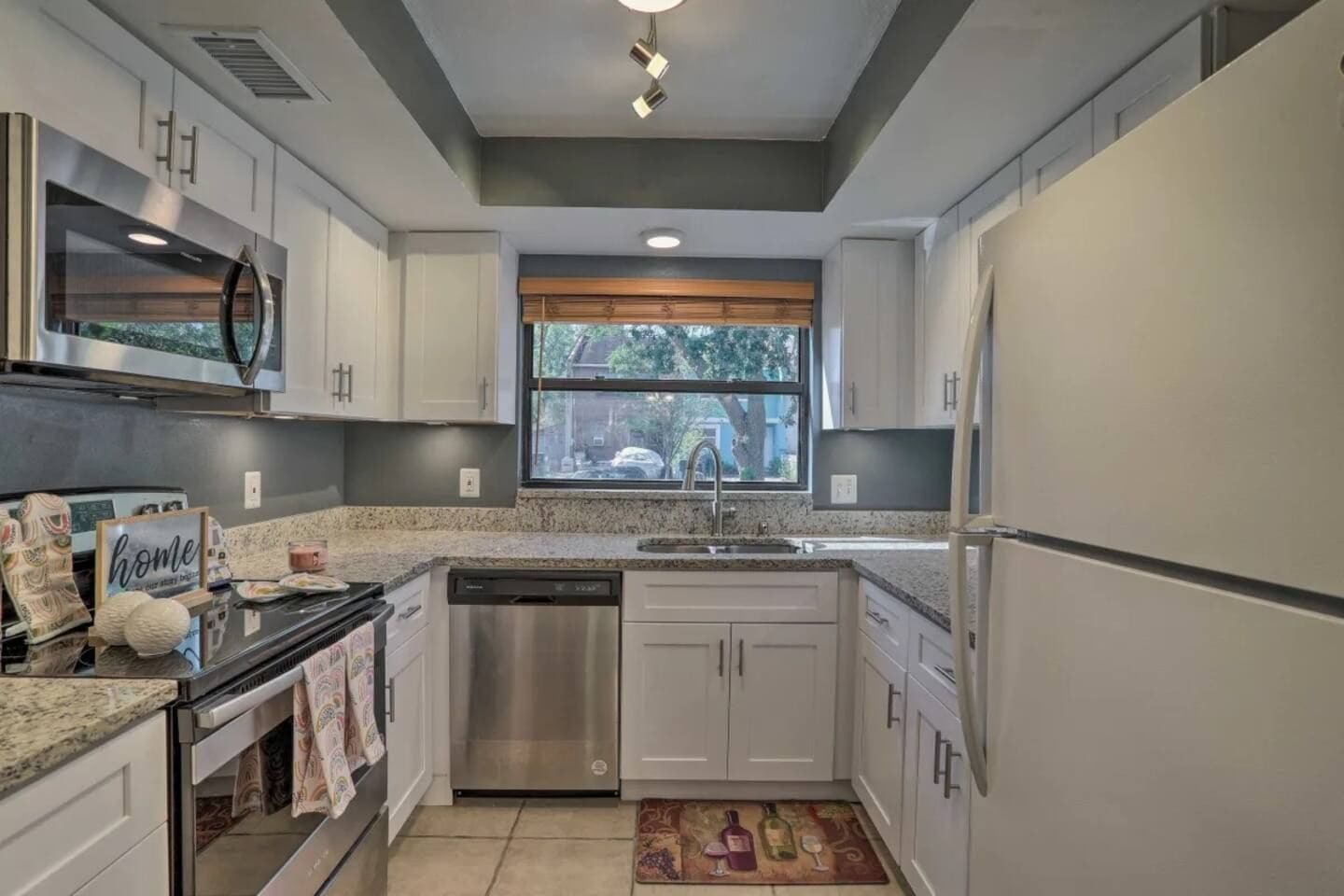 A modern kitchen with stainless steel appliances, a granite countertop, and a window with a view of the outdoors.