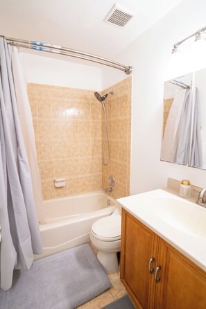 Ein Badezimmer mit einer Badewanne, Toilette und einem Waschbecken mit Spiegel.