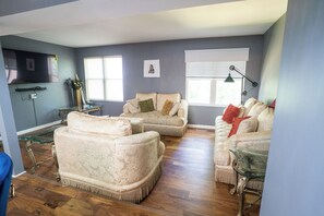 Ein Wohnzimmer mit zwei Sofas, einem Glastisch und einer Lampe.