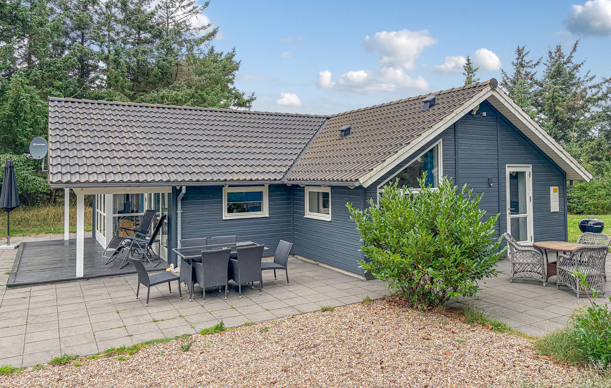 A two-story house with a covered patio, outdoor furniture, and a small garden area.