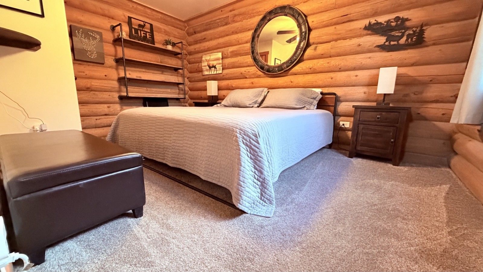 A log cabin bedroom with a bed, bedside tables, and a mirror.
