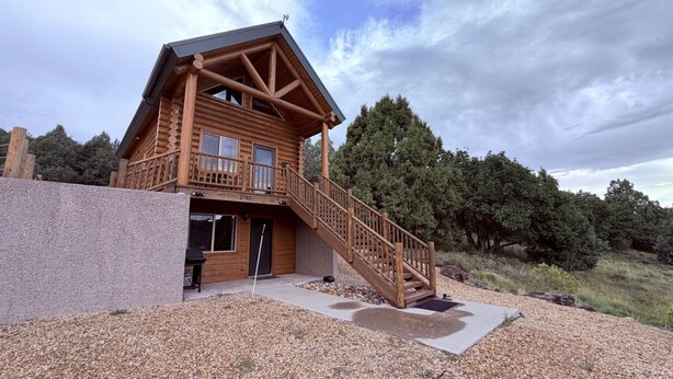 Eine Blockhütte mit Balkon, Treppe und einem Schotterweg.