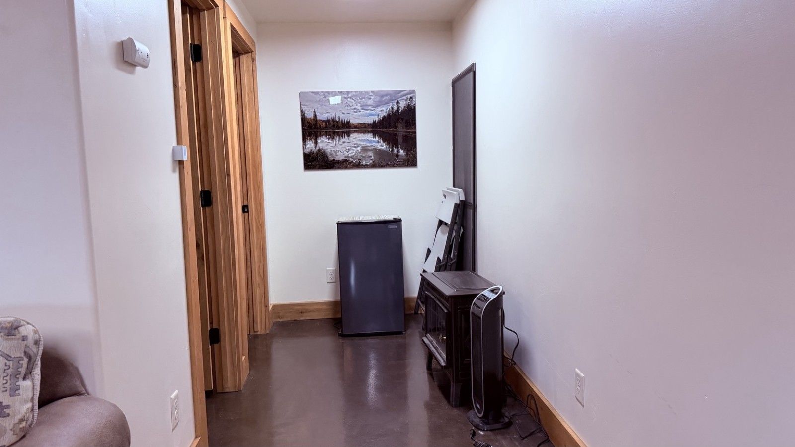 A hallway with a wooden door, a refrigerator, a TV stand, and a painting on the wall.