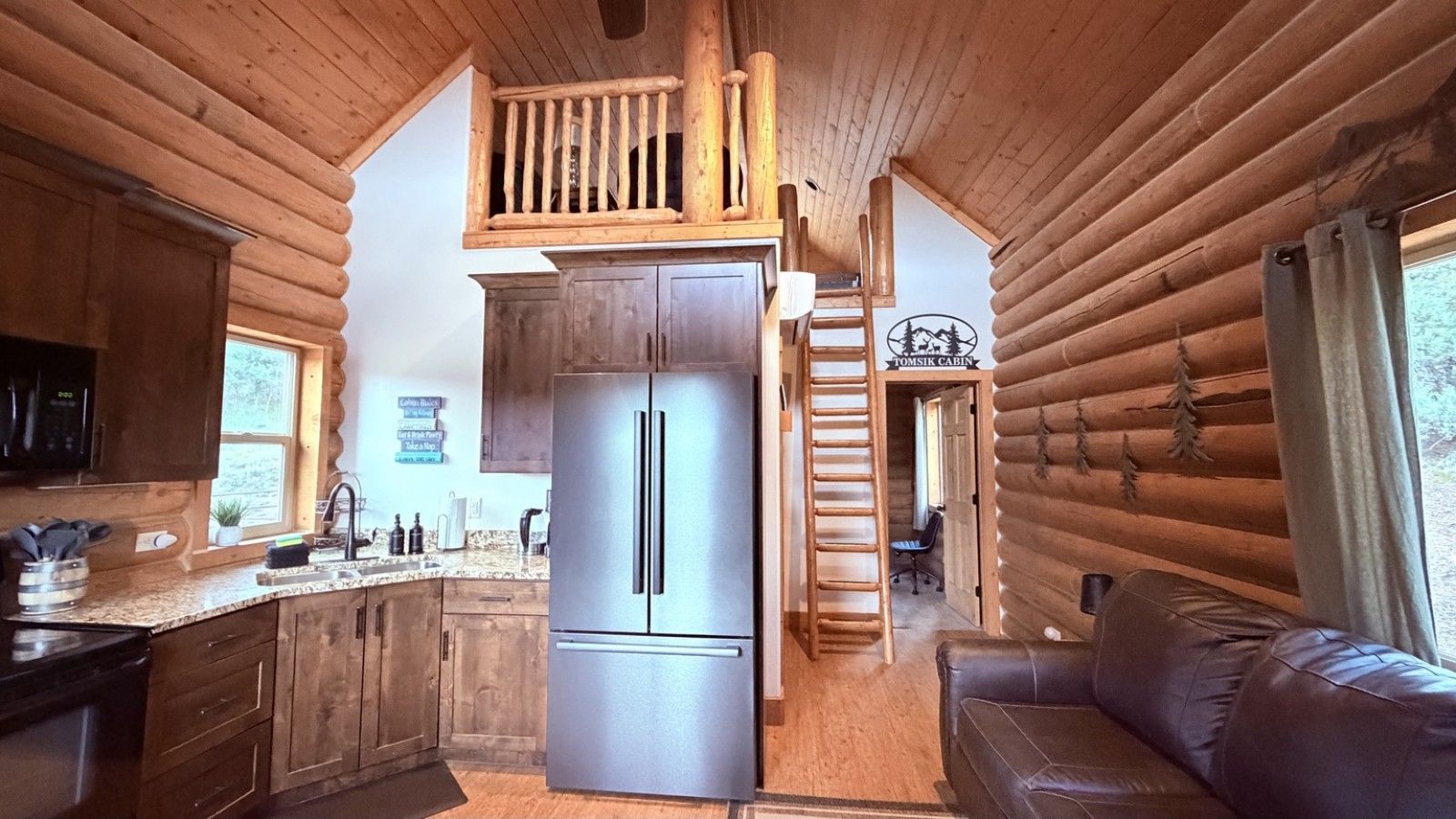 A log cabin interior with a kitchen, a dining area, and a living room.