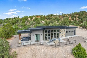 Uma casa moderna de dois andares com área de pátio, janelas amplas e fachada de pedra.