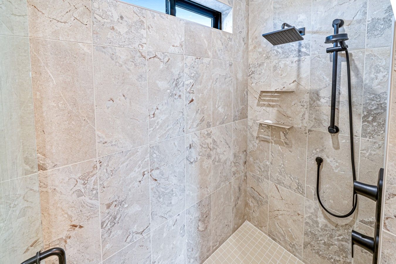 Un bagno con doccia, pareti piastrellate e una finestra.