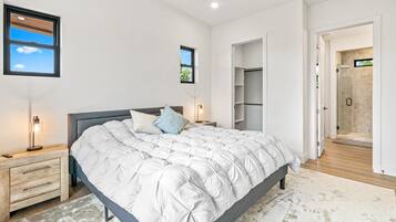 Una camera da letto con un letto grande, comodini, un armadio e un angolo doccia.