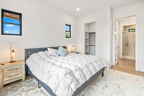 Un dormitorio con una cama grande, mesitas de noche, un armario y zona de ducha.