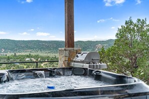 Banheira de hidromassagem com estrutura de pedra e churrasqueira, com vista para uma paisagem deslumbrante.