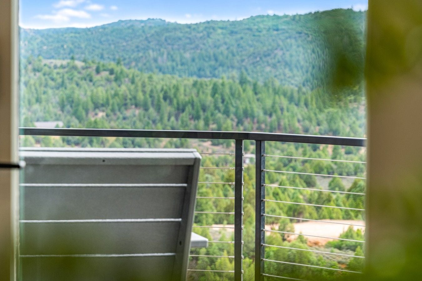 Ein Balkon mit Metallgeländer und Blick auf eine bewaldete Berglandschaft.