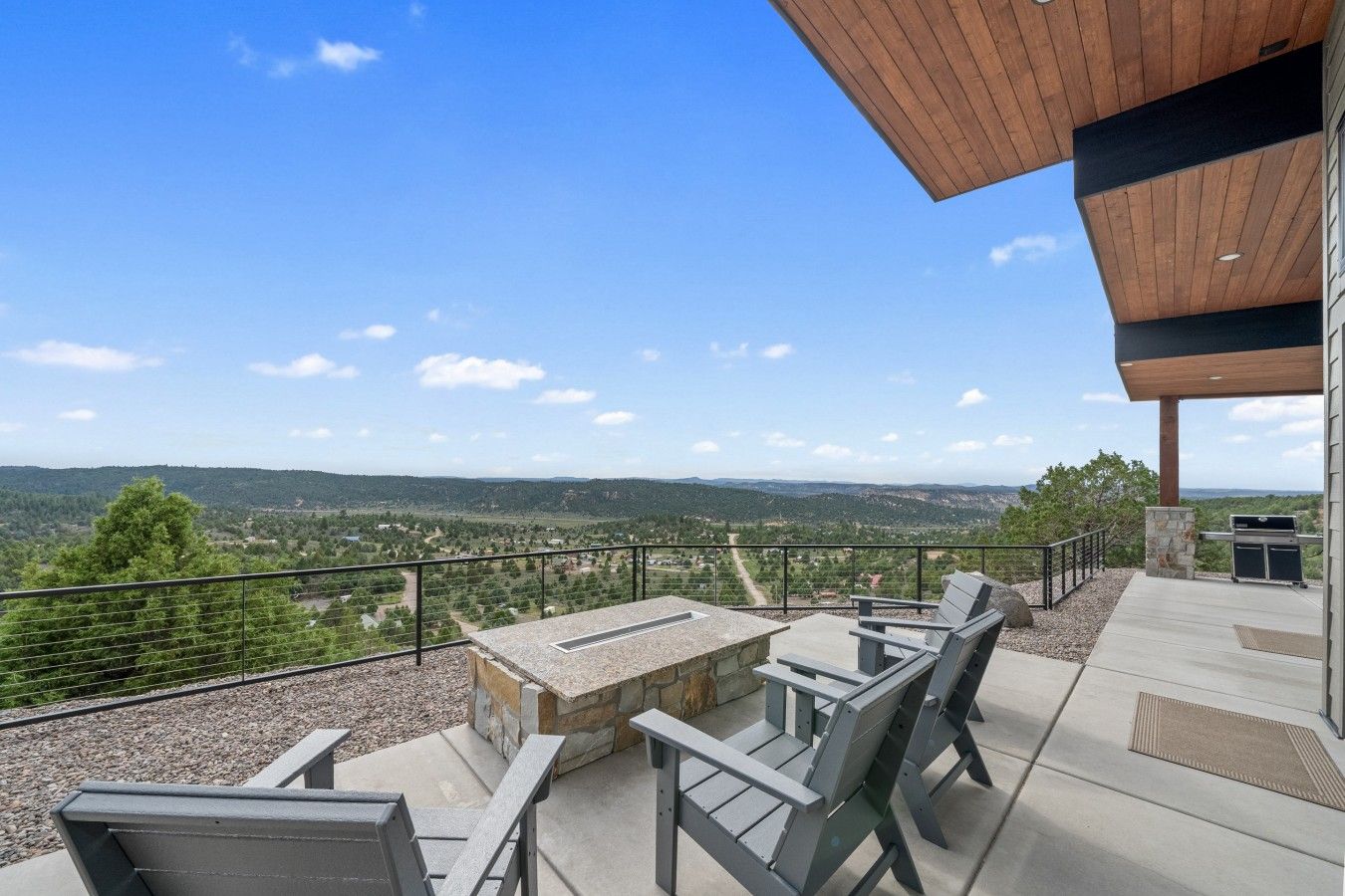 A patio with outdoor seating and a view of a hilly landscape.