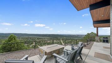 A patio with outdoor seating and a view of a hilly landscape.