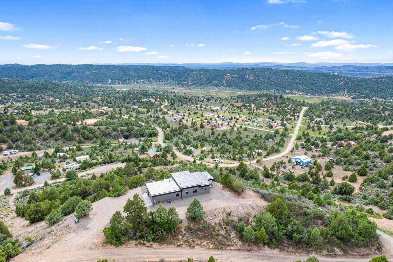 Ländliche Landschaft mit verstreuten Gebäuden, Straßen und dichtem Grün.