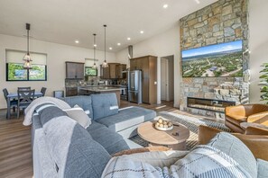 A modern living room with a sectional sofa, a fireplace, and a kitchen area with a stone accent wall.