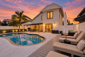 A modern house with a swimming pool, outdoor seating, and a patio area.