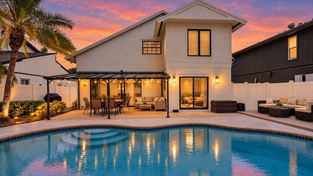 A two-story house with a swimming pool, outdoor seating, and a covered patio area. - Navigate Stays Delray Beach, FL, Pool - Near Beach (Delray Beach)