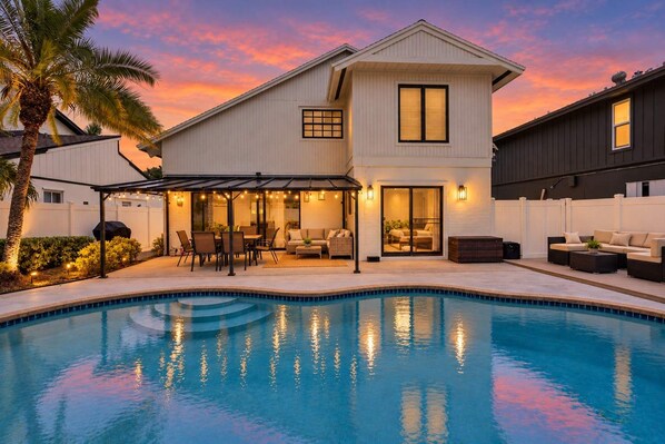 A two-story house with a swimming pool, outdoor seating, and a covered patio area.