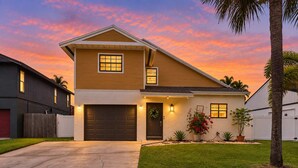 A two-story house with a garage, a front porch, and a well-maintained lawn. - Navigate Stays Delray Beach, FL, Pool - Near Beach (Delray Beach)