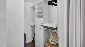 Een inloopkast met open planken, een kledingroede en een opgevouwen handdoek op een plank.