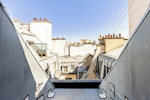 A narrow alleyway between buildings with multiple chimneys and a clear sky. - Maraisette - Métro - 4ème arrondissement (Paris)
