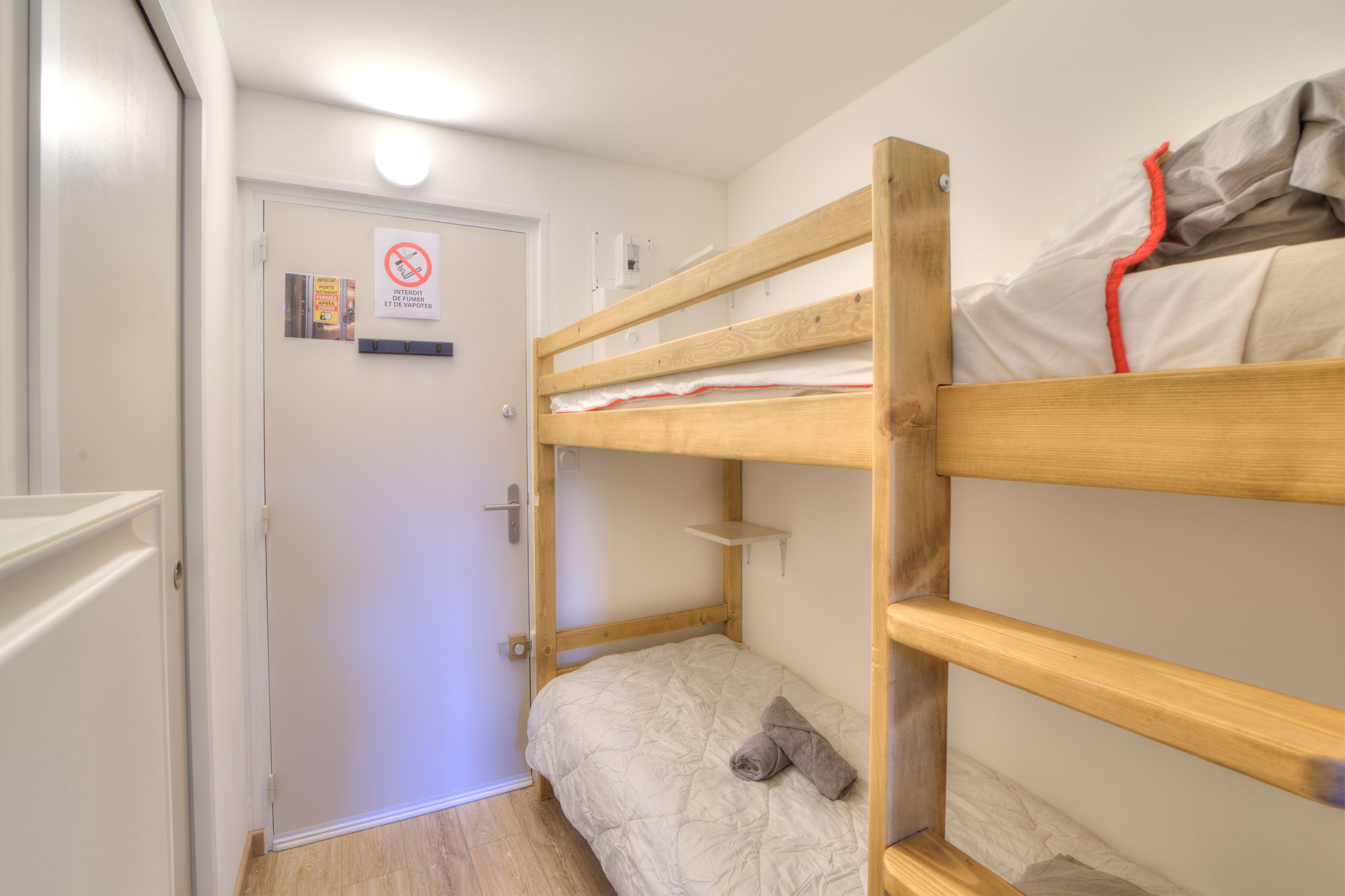 A bunk bed room with a door, a sign, and a small shelf.
