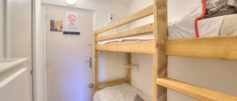 A bunk bed room with a door, a sign, and a small shelf.