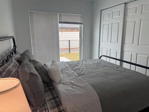 A bedroom with a bed, pillows, a lamp, and a sliding glass door leading to an outdoor area.