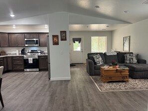 A modern kitchen with dark wood cabinets, stainless steel appliances, and a marble countertop.