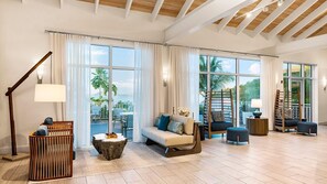 A spacious living room with a large window, a sofa, a coffee table, and a wooden chair. - Studio at Limetree Beach Resort by Club Wyndham on Beautiful St. Thomas (Southside)
