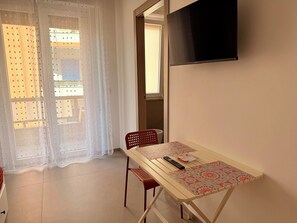 A room with a table, chairs, a TV, and a window with curtains. - WALK37 Syracuse - Between the Greek Theater and Ortigia (Siracusa)