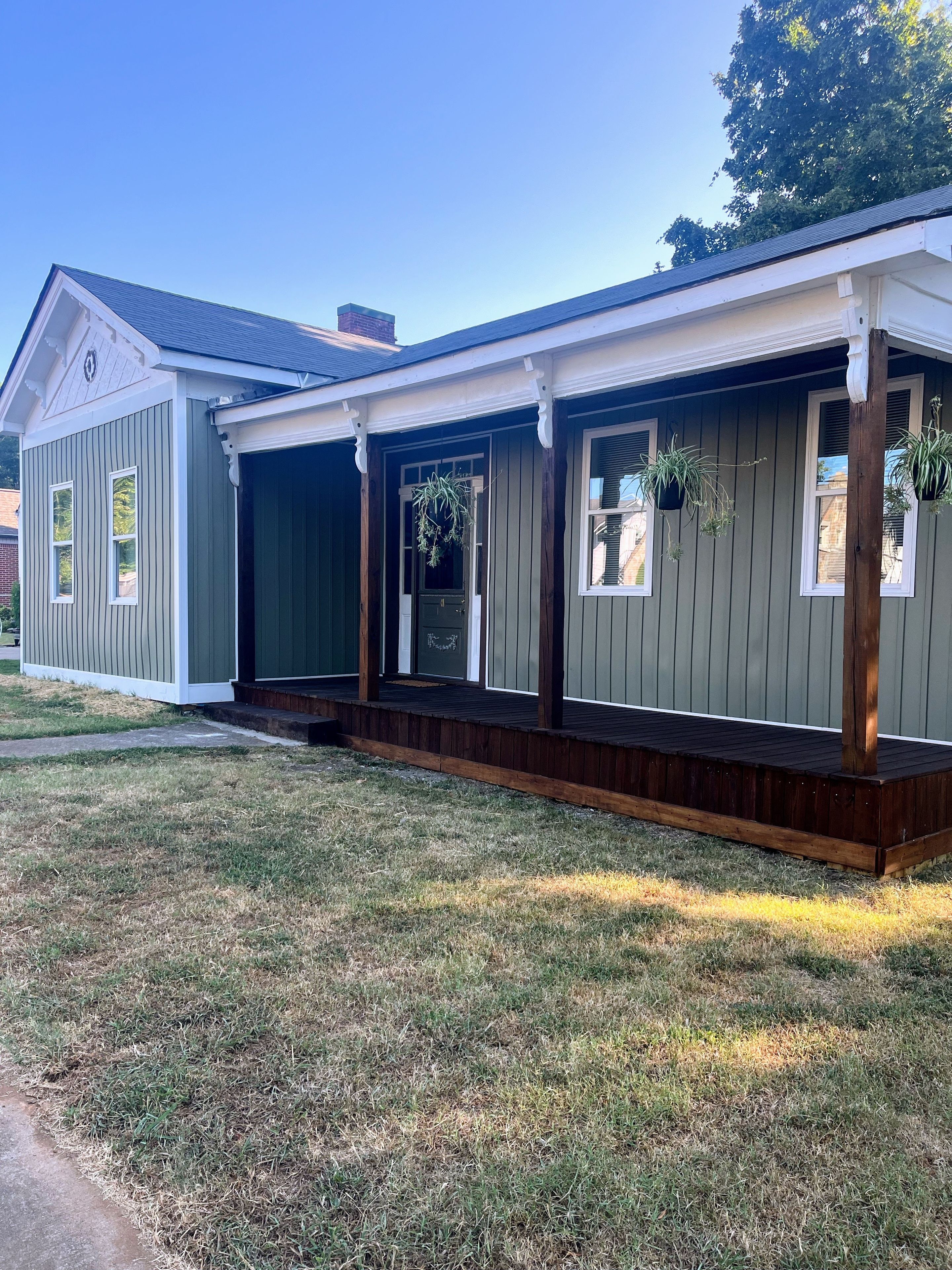 A residential building with a covered porch, a front door, and windows.