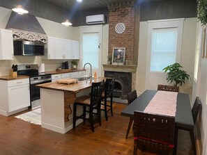 Una cocina con una isla central, armarios blancos, un microondas y una chimenea.