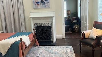 Een kamer met een bed, een open haard, een stoel en een vloerkleed.