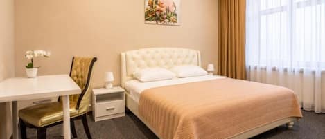 Une chambre d’hôtel avec un lit, un bureau, une chaise et une table de chevet.